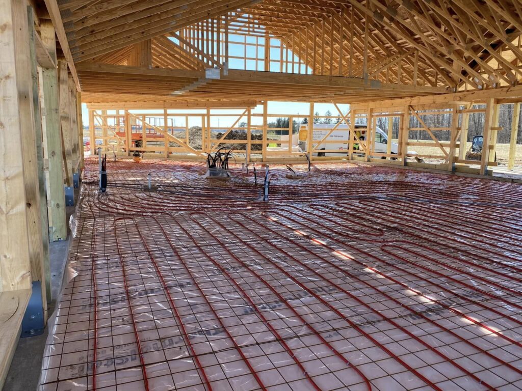Radiant floor heating tubing laid over reinforcing mesh in a large post-frame building before the concrete pour