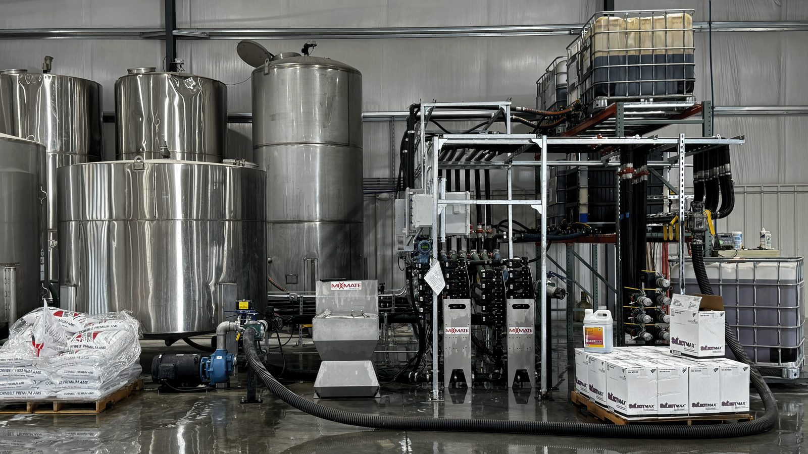 Mixmate Pro stationary chemical mixing plant with Mixmate inductors, stainless steel tanks, totes and metering manifold inside the new Farm Service Cooperative plant