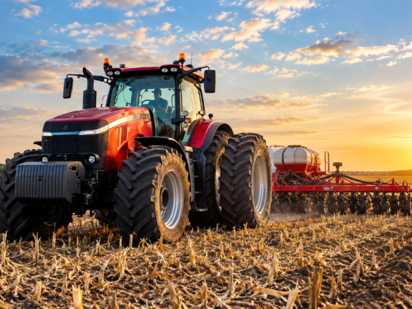 image Red tractor pulling a planter through a field at sunset